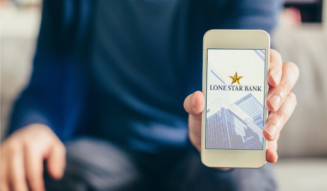 A person holding a mobile phone with the Lone Star Bank mobile app on screen