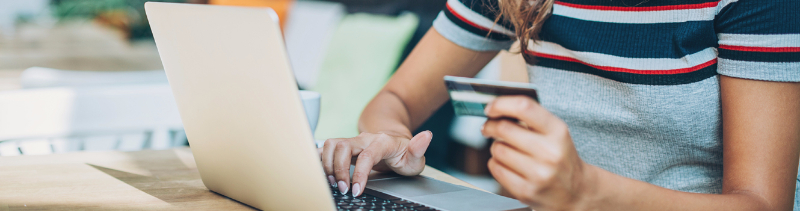 A girl holding her credit card and typing on her laptop.