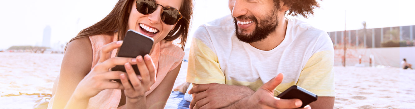 A couple on a beach looking at a mobile phone