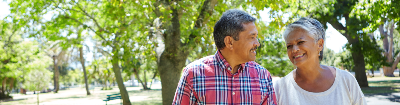 A middle age couple walking in a wooded area on a sunny day