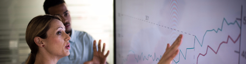 A woman explains her business plans and statistics to another employee.