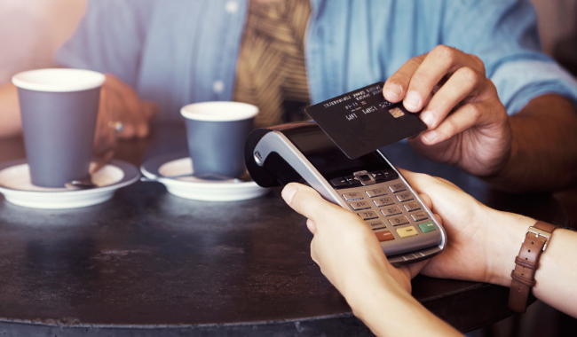 A young man paying for coffee with a debit or credit card